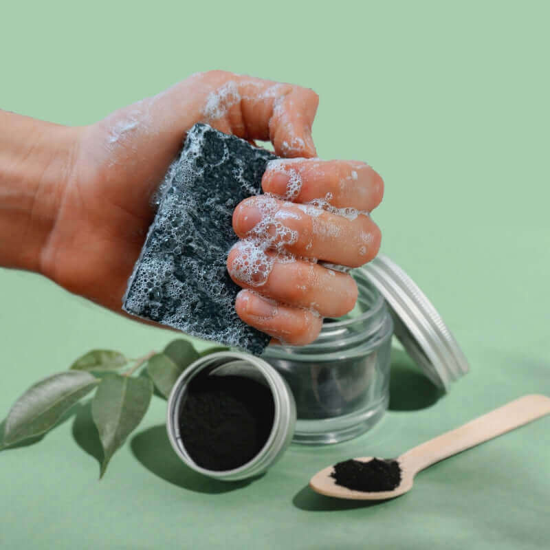 Wulf Body Bar - Hand holding Charcoal Mint exfoliating soap bar demonstrating size, exfoliating salt texture, and creamy lather.
