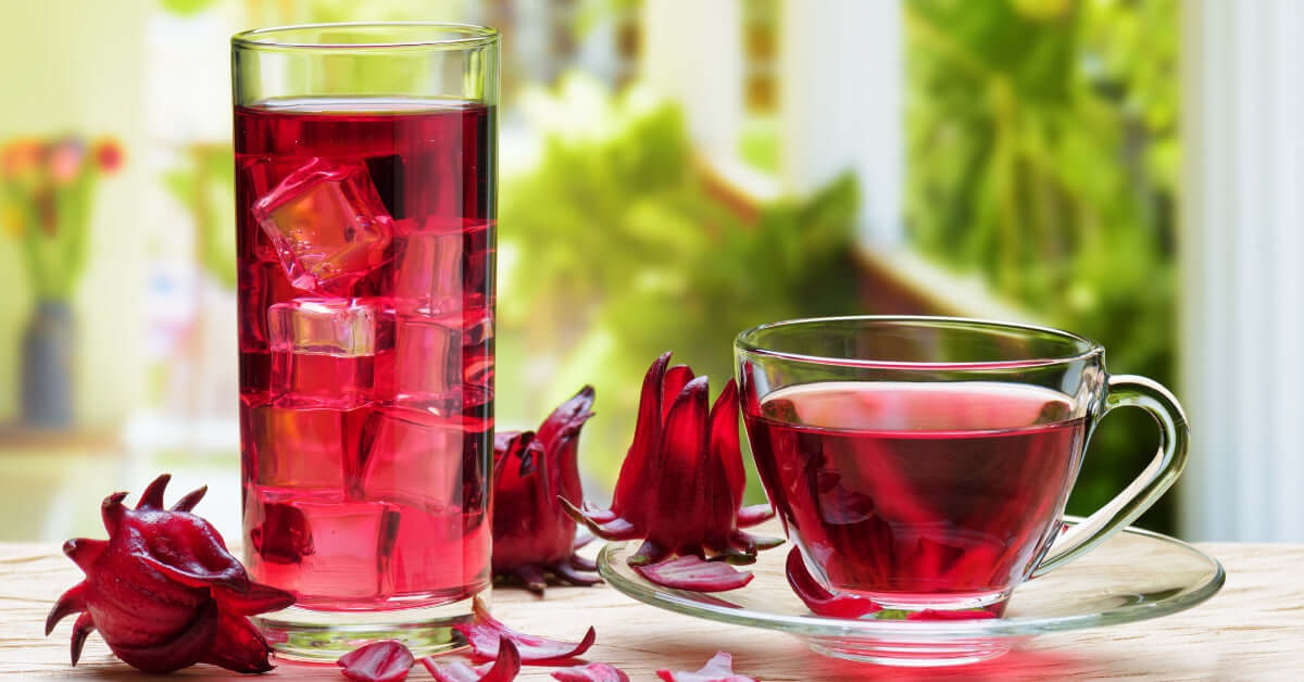 BioFermented Australian Botanicals drink served in a glass and a cup, surrounded by hibiscus flowers.