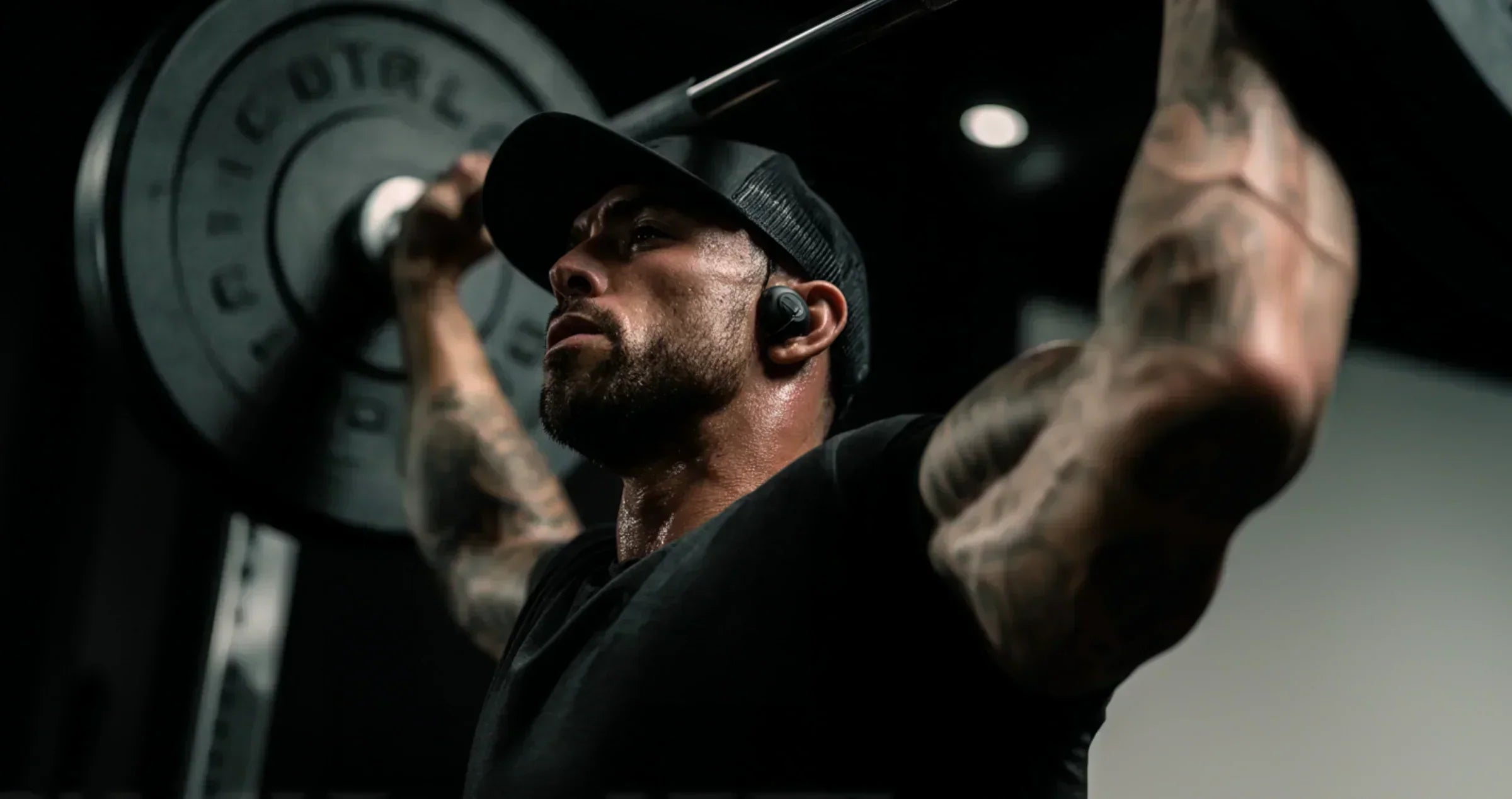 A muscular man lifting a barbell, showcasing the importance of mTOR muscle growth activation in strength training.